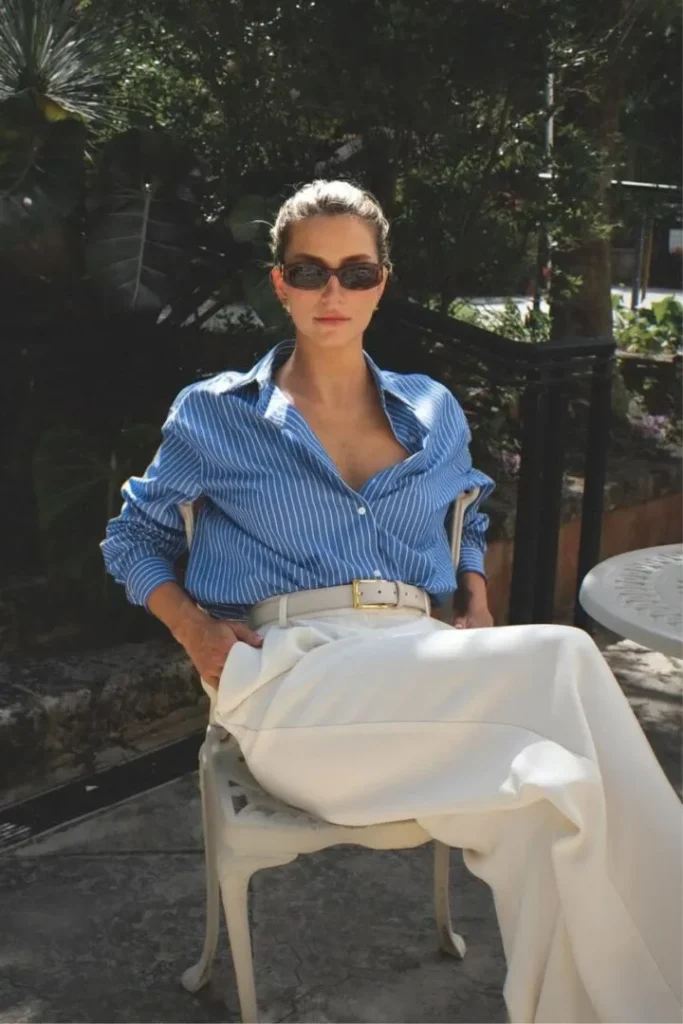 Elegant spring outfit with blue striped shirt tucked into white trousers, capturing old money style.