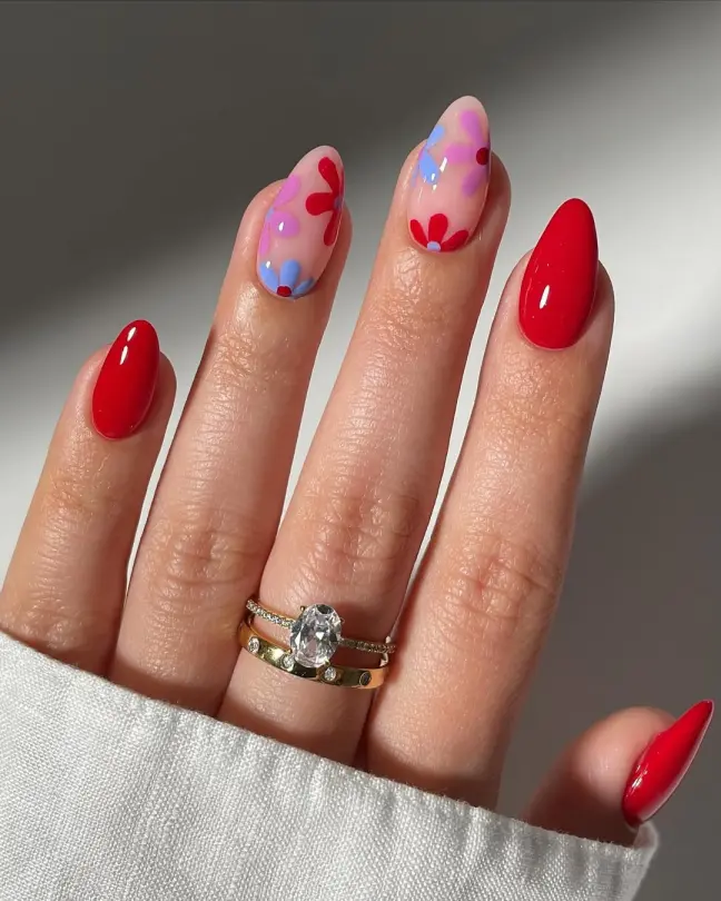 Bright and fun Stunning Nail Ideas combining glossy red nails with accent floral art in red, pink, and blue on a nude base.
