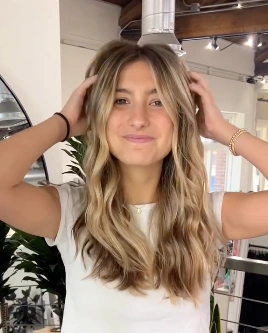 Hairstyles for Medium Length Hair featuring soft beach waves and subtle blonde highlights for a relaxed, sun-kissed vibe.