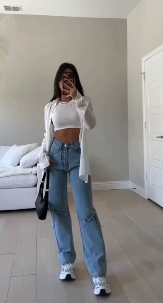 Spring Outfit Ideas combining a white crop top and oversized shirt with distressed jeans and chunky sneakers for a sporty casual vibe.