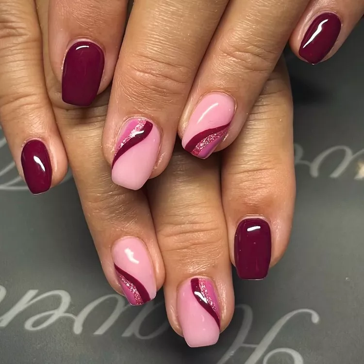 Short fall nail designs in burgundy and pink with glittery diagonal wave accents.