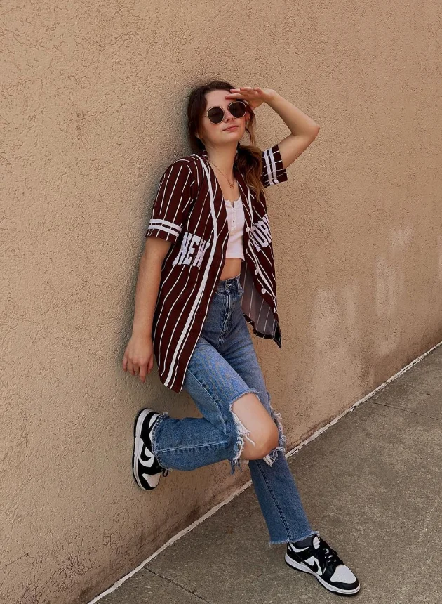 Early Fall Outfit with a sporty-casual vibe – ripped mom jeans, white crop top, and a maroon striped baseball shirt, paired with black-and-white sneakers.