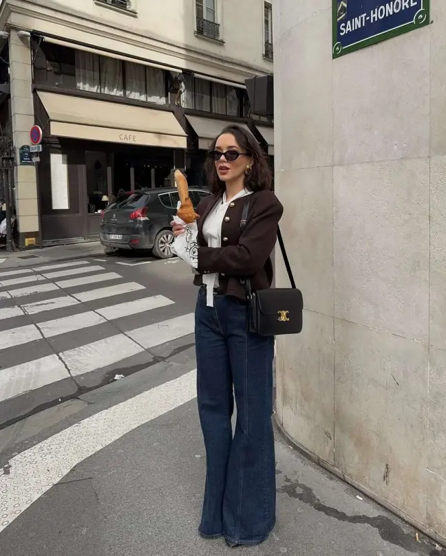 Dark cropped jacket, flared jeans, and designer handbag styled with a vintage flair in a springtime old money look.