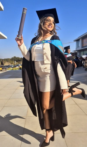 Graduation outfit ideas – cream tweed two-piece skirt suit under a black gown with blue trim, styled with black heels and a graduation cap for a classy academic look.