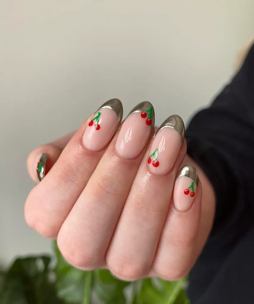 Nude almond nails with metallic silver French tips and classic cherry nail art.