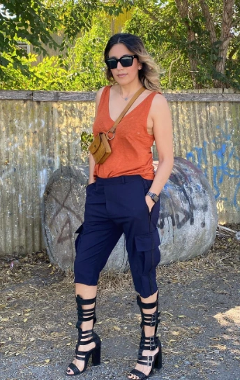 Stylish Cargo Shorts Outfit with cropped black tactical pants, a rust orange tank top, and gladiator heels, topped with a mini crossbody bag.