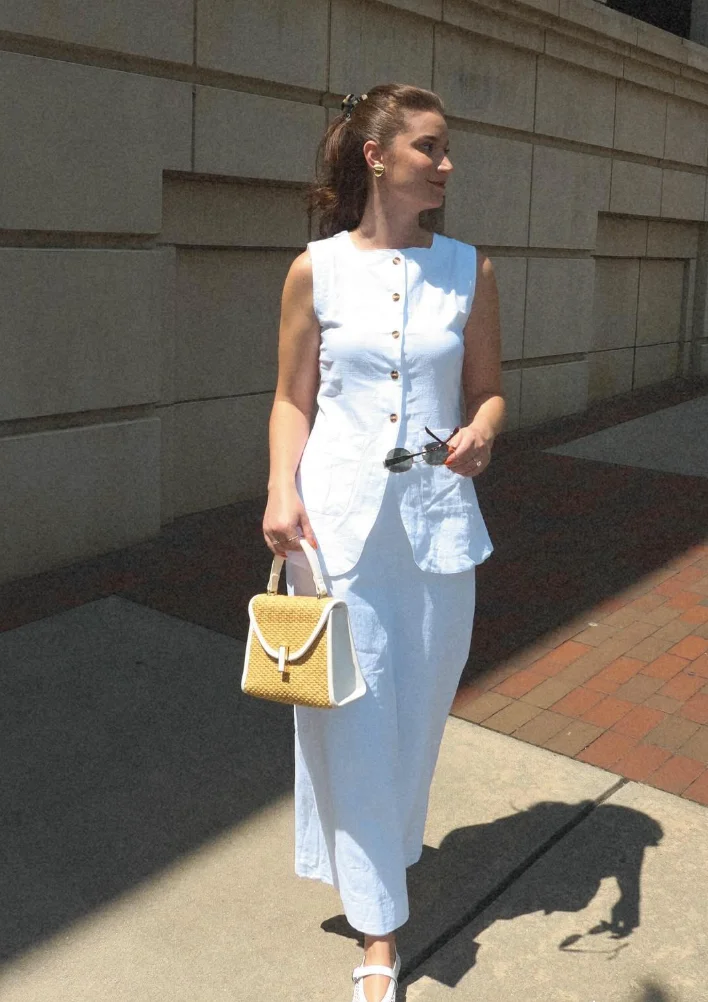 Early Fall Outfit in crisp white – sleeveless button-down top and midi skirt, accessorized with a structured straw bag and white sandals for a clean, fresh look.