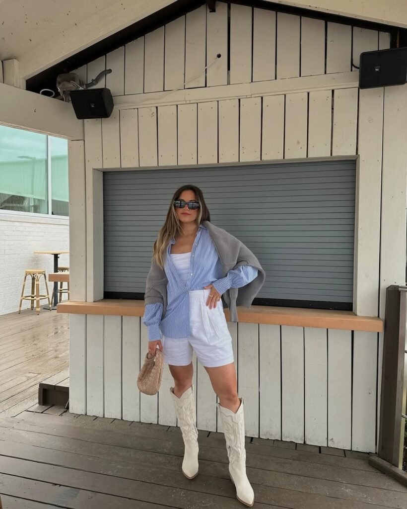 Spring Outfit Ideas featuring white shorts, a striped button-up shirt, and tall white cowboy boots, layered with a grey sweater for a preppy look.