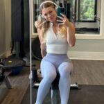 Gym outfit inspo with a white zip-up crop top and light lavender high-waisted leggings in a gym selfie.