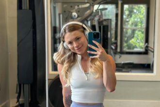 Gym outfit inspo with a white zip-up crop top and light lavender high-waisted leggings in a gym selfie.
