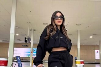 Fashionable traveler in all-black sweatsuit and designer bag walking confidently – classic all-black airport outfit.