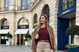 Woman in a maroon top and beige wide-leg trousers, layered with a camel coat – an elegant outfit suited for fall street style.
