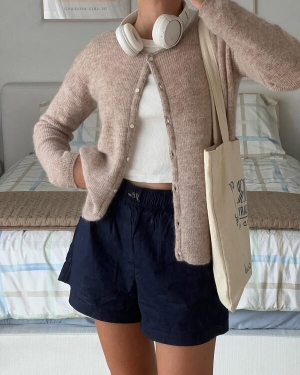 Casual cardigan outfit with a light brown fuzzy cardigan and navy shorts, accessorized with headphones and a tote bag.