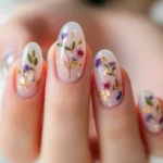 Summer Nail Ideas featuring translucent nails with pressed flower designs and gold foil accents – a perfect blend of natural and elegant.