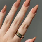 Almond-shaped neutral nails in a rich terracotta nude tone with a glossy finish.