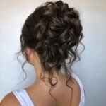 Elegant hairstyle in a tousled, textured updo with romantic face-framing tendrils.