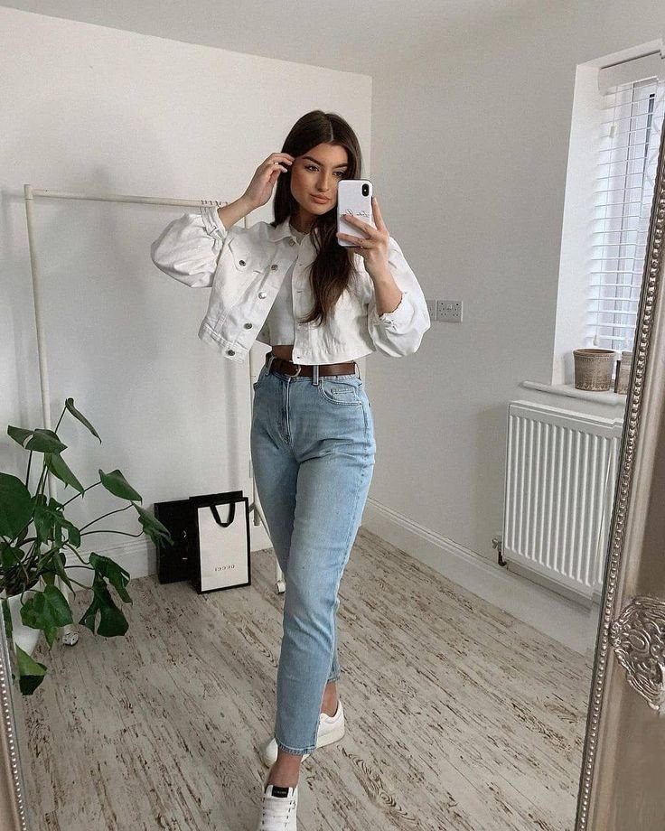 Light denim jeans and a cropped white jacket paired with white sneakers for a crisp everyday outfit. Outfits Casuales.
