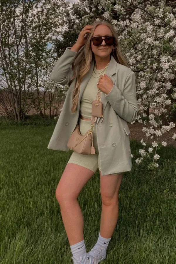 Soft pastel green monochrome biker shorts outfit with a matching blazer and crop top, accessorized with a beige crossbody mini bag.