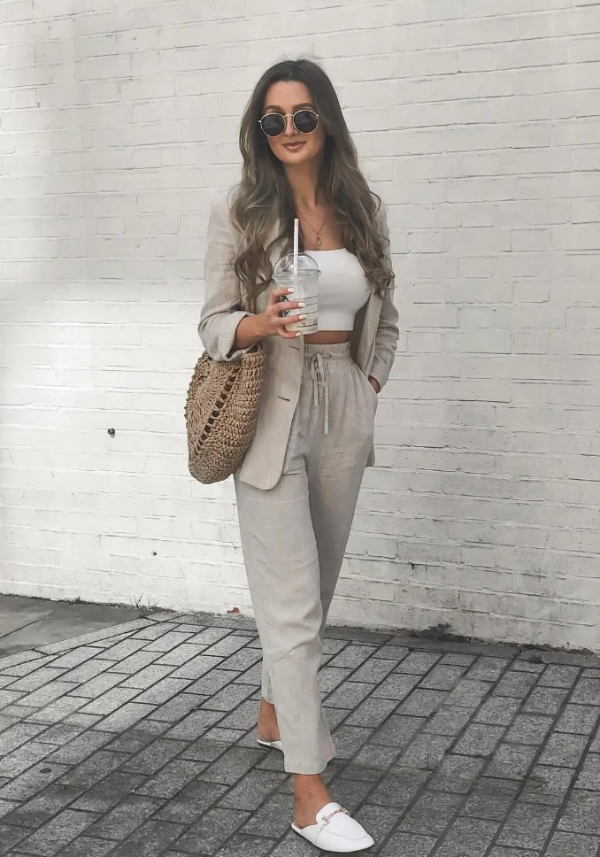 Woman wearing a light beige linen pantsuit with a white cropped top and loafers—smart casual take on modest summer outfits with modern flair.