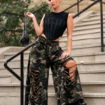 Edgy Camouflage Pants Outfit styled with wide-leg shredded camo pants, a black corset-style tank top, and combat boots.