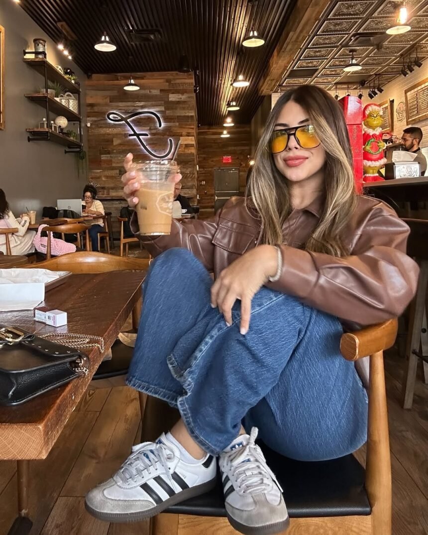 Casual coffee date outfit featuring a brown leather jacket, denim jeans, and Adidas sneakers.