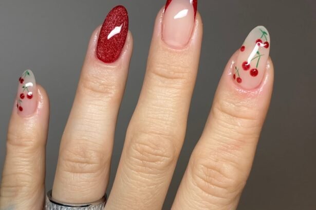 Almond nails with glittery red polish, red French tips, and cherry nail art on nude bases.