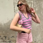 A cute simple outfit in soft pastels – pink striped sweater vest, pink high-waisted shorts, and a quilted cream handbag with floral accents, giving off sweet retro vibes.